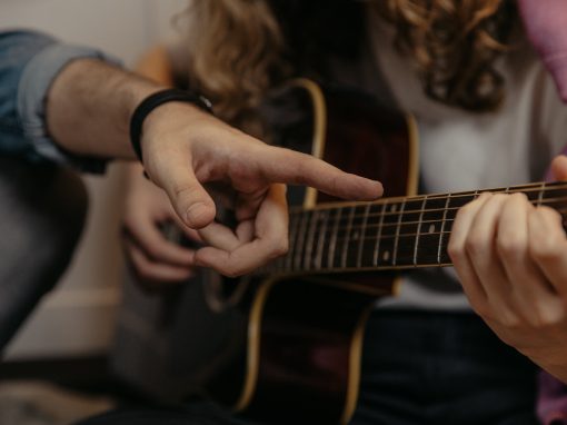 Photographie en plan rapproché d'une jeune femme apprenant des accords de guitare avec son instructeur
