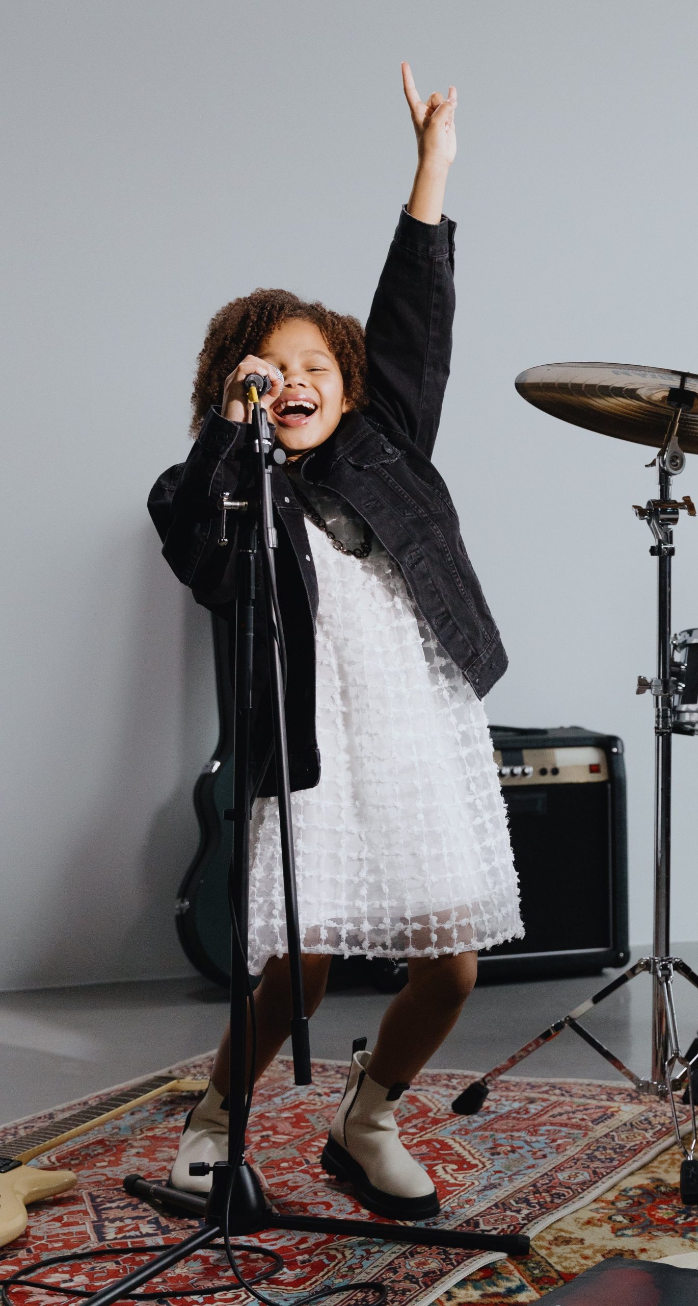 Une petite fille noire chante au micro, devant un ampli et près d'une cymbale de batterie