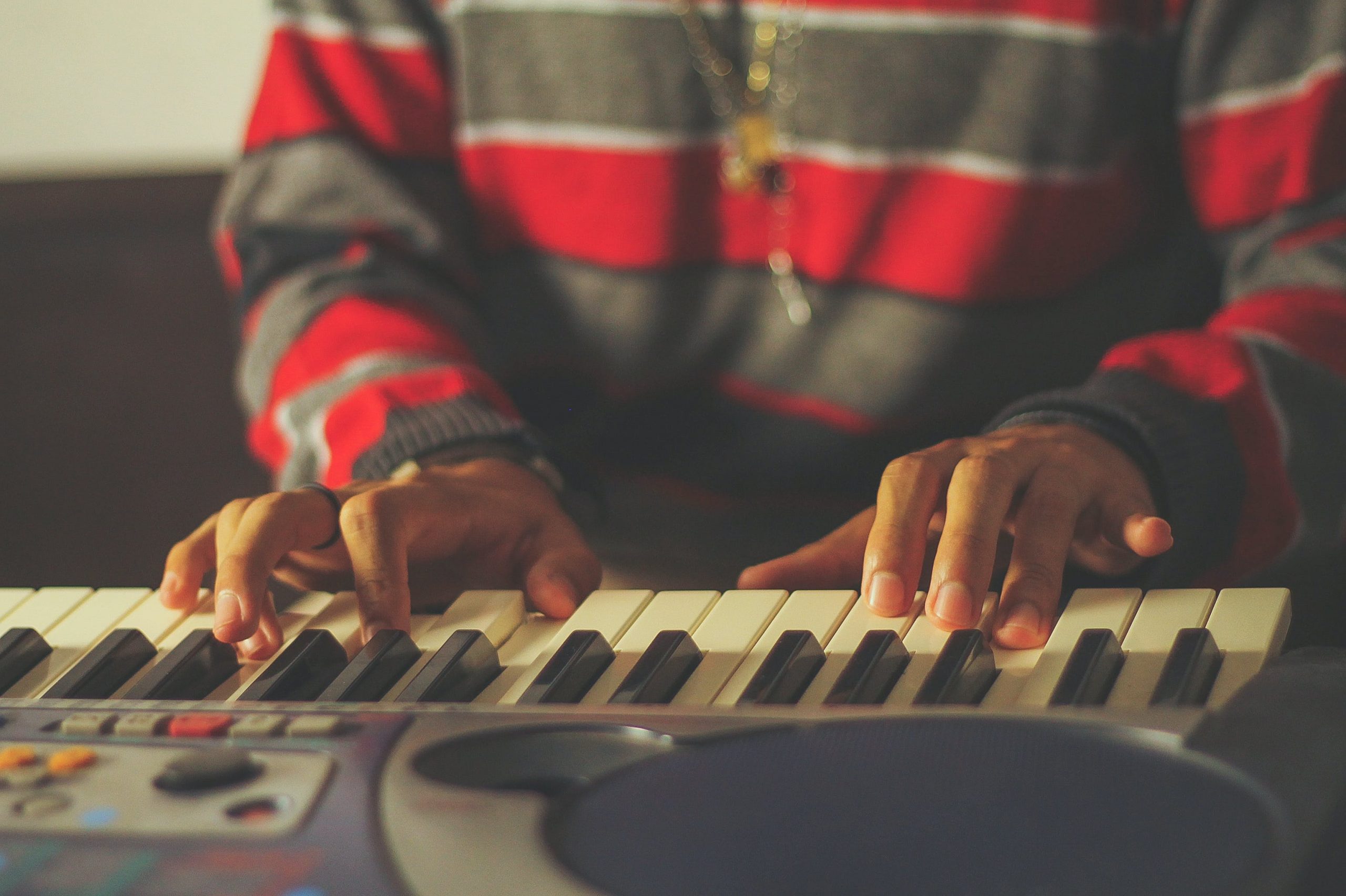 Plan rapproché sur un jeune homme noir qui joue sur un piano électronique